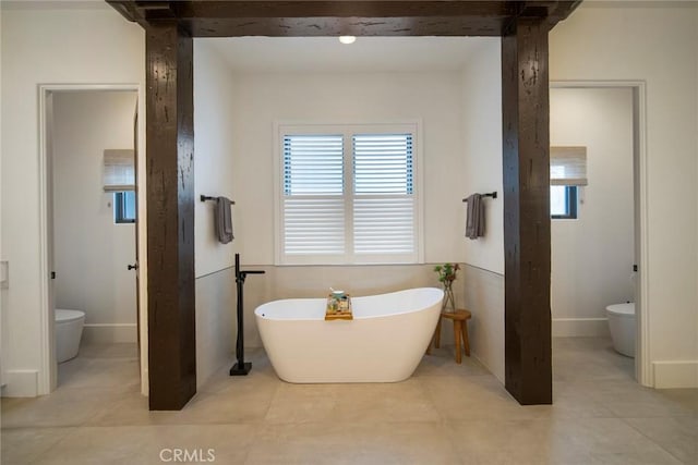 bathroom featuring tile patterned flooring, a tub, and toilet