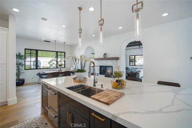 kitchen with plenty of natural light, light stone countertops, sink, and hanging light fixtures