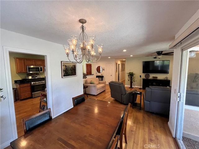 dining area featuring hardwood / wood-style flooring, ceiling fan with notable chandelier, and a textured ceiling