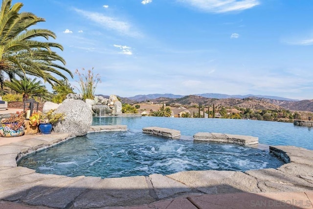 view of swimming pool with a water and mountain view