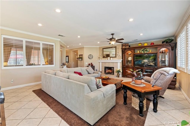 tiled living room with crown molding, ceiling fan, and a fireplace