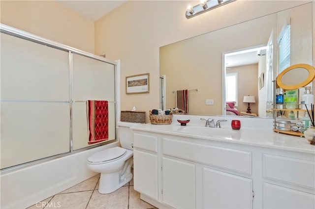 full bathroom with toilet, tile patterned floors, vanity, and bath / shower combo with glass door