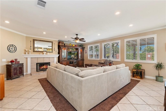 living room with light tile patterned floors, ornamental molding, a tile fireplace, and ceiling fan