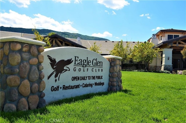 community sign featuring a mountain view and a yard