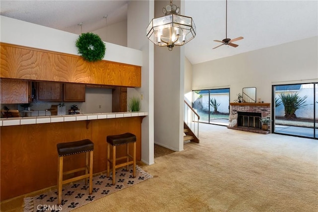 kitchen with light carpet, decorative light fixtures, tile counters, and high vaulted ceiling