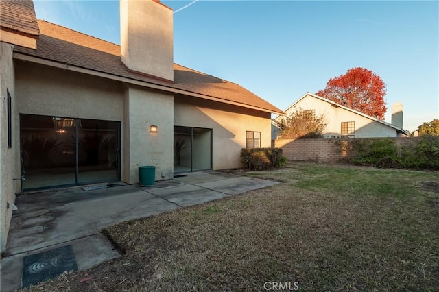 rear view of house with a patio and a lawn