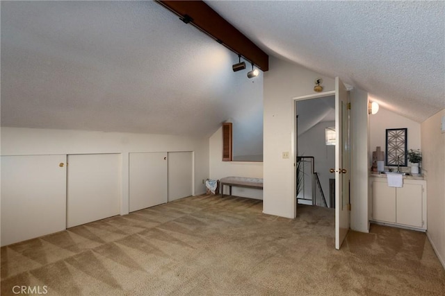 bonus room with light colored carpet, a textured ceiling, and vaulted ceiling with beams