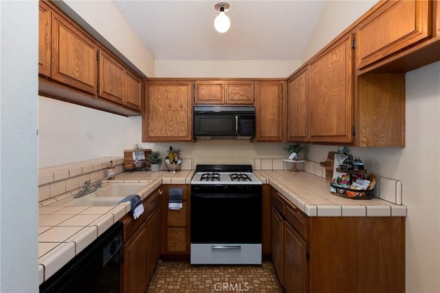 kitchen with lofted ceiling, sink, tile counters, and black appliances