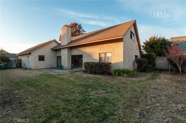 back of property with a yard and a patio