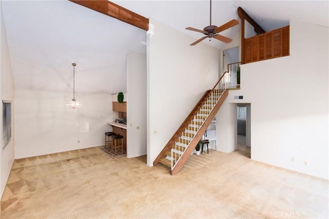 unfurnished living room with beamed ceiling, carpet, and high vaulted ceiling