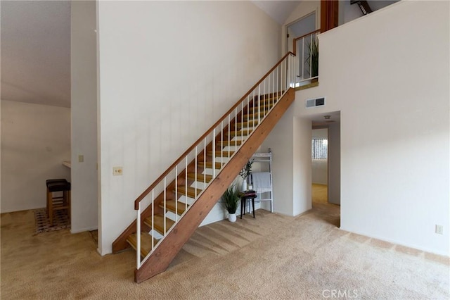 stairs featuring high vaulted ceiling and carpet