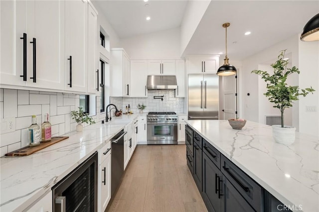 kitchen featuring pendant lighting, white cabinetry, beverage cooler, premium appliances, and light stone counters