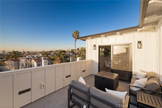 patio terrace at dusk featuring a balcony and an outdoor fire pit