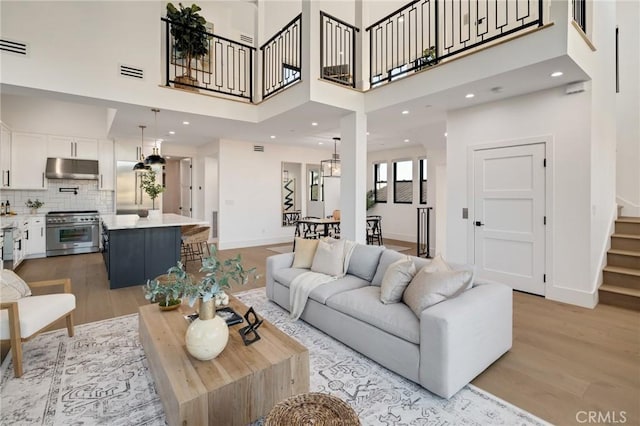 living room with a towering ceiling and light wood-type flooring