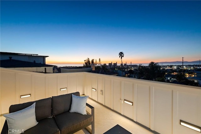 patio terrace at dusk featuring a balcony