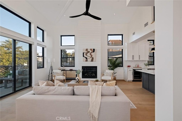 living room with radiator, high vaulted ceiling, a fireplace, wine cooler, and light hardwood / wood-style flooring