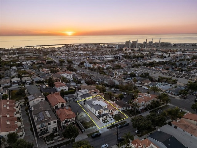 aerial view at dusk featuring a water view