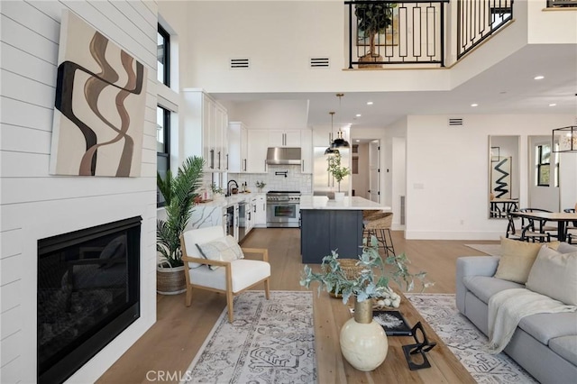 living room with sink, light hardwood / wood-style floors, and a towering ceiling