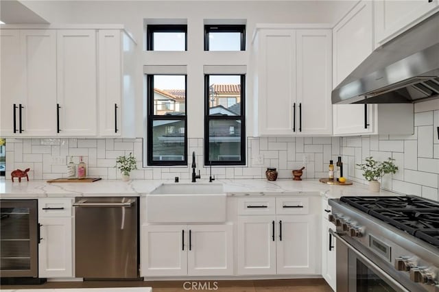 kitchen featuring stainless steel appliances, light stone countertops, white cabinets, and wine cooler