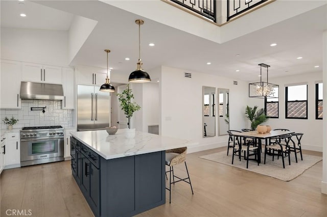 kitchen with white cabinetry, high quality appliances, a center island, and hanging light fixtures