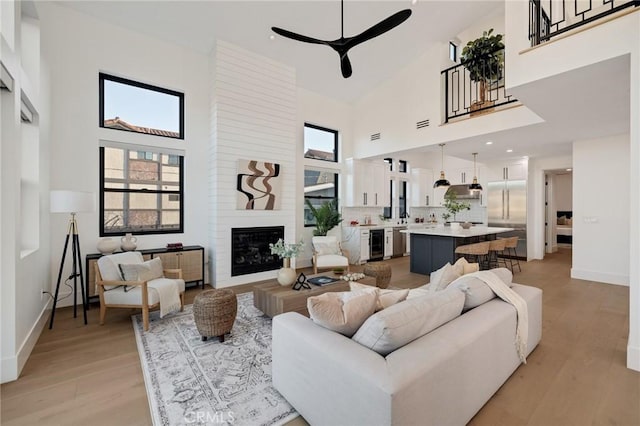 living room featuring a large fireplace, a wealth of natural light, and light hardwood / wood-style flooring