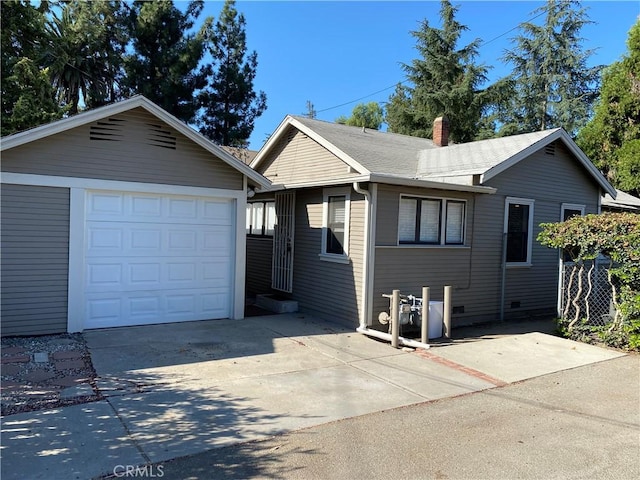 single story home with an outdoor structure, a detached garage, driveway, and a chimney