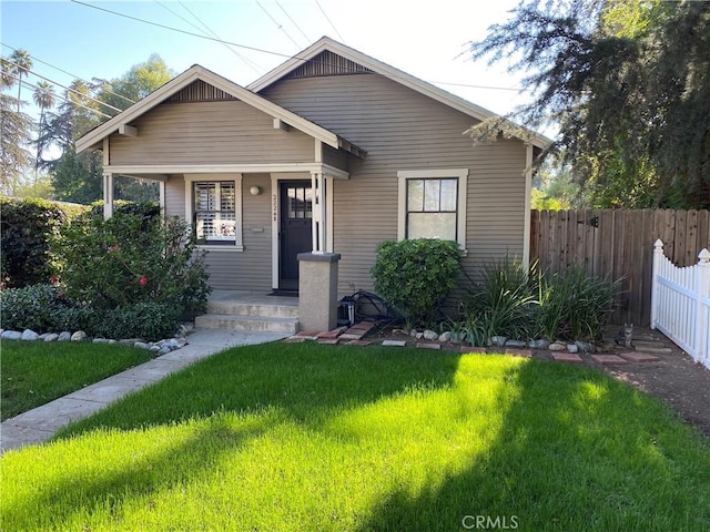 bungalow with a porch, a front lawn, and fence