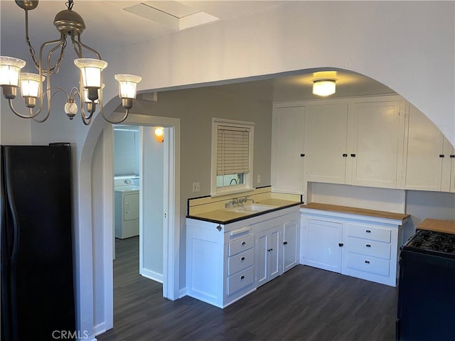 kitchen featuring dark wood finished floors, freestanding refrigerator, a sink, white cabinetry, and gas range