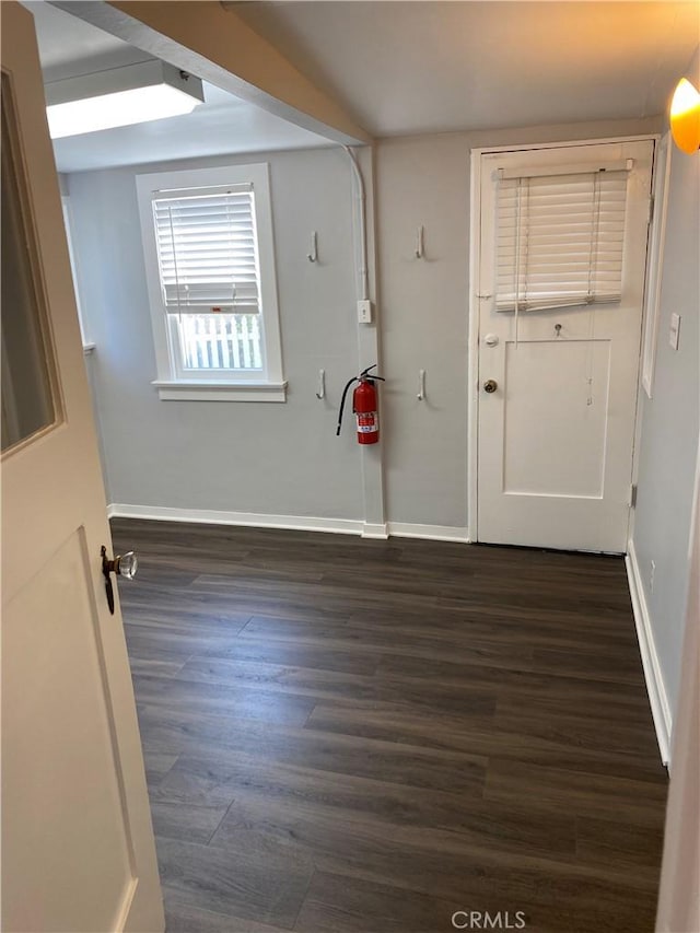 spare room with baseboards and dark wood finished floors