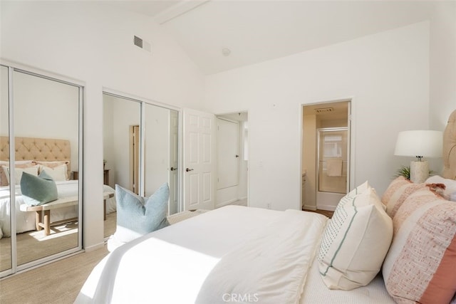 bedroom with multiple closets, light colored carpet, ensuite bathroom, and vaulted ceiling with beams