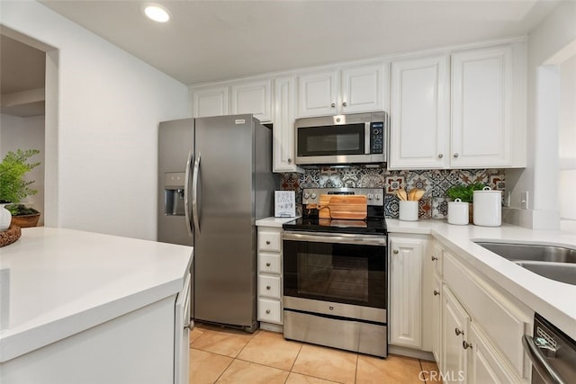 kitchen featuring stainless steel appliances, light tile patterned flooring, backsplash, and white cabinetry