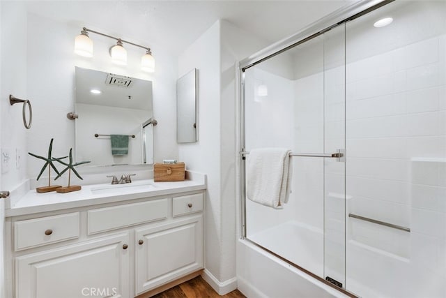 bathroom featuring bath / shower combo with glass door, wood-type flooring, and vanity