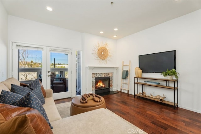 living room with dark wood-type flooring, a tile fireplace, and french doors