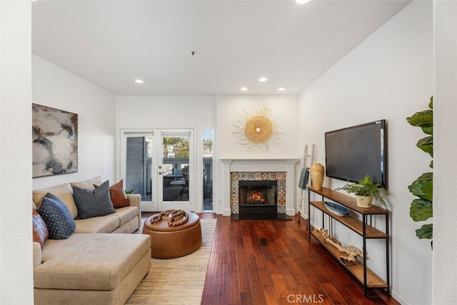 living room with a tiled fireplace and wood-type flooring