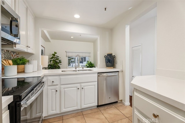 kitchen featuring stainless steel appliances, white cabinetry, sink, and light tile patterned floors