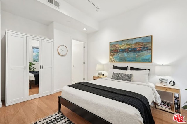 bedroom featuring track lighting and light hardwood / wood-style floors