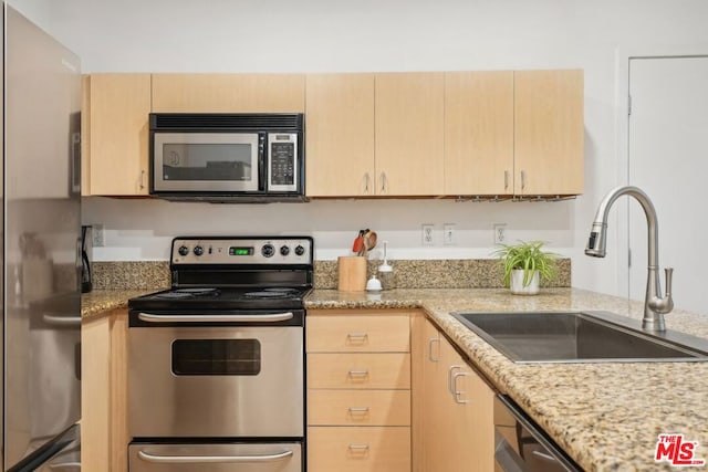 kitchen with light brown cabinetry, sink, light stone counters, and stainless steel appliances