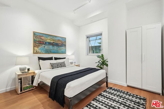 bedroom featuring track lighting and light hardwood / wood-style floors