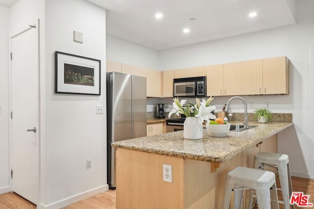 kitchen featuring light hardwood / wood-style flooring, stainless steel appliances, light stone countertops, kitchen peninsula, and light brown cabinets