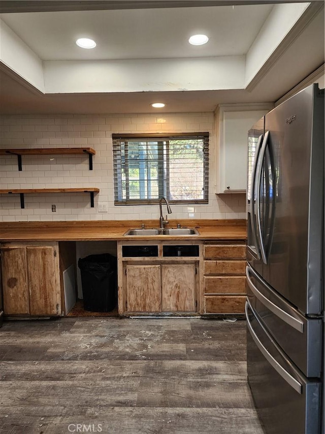 kitchen with sink, dark wood-type flooring, stainless steel fridge, decorative backsplash, and a raised ceiling