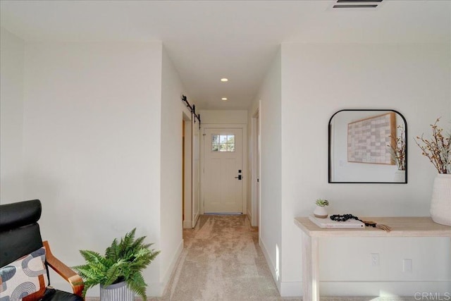 hallway featuring light colored carpet and a barn door