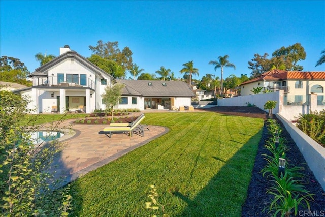 back of property featuring a balcony, a yard, and a patio