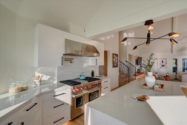 kitchen featuring double oven range, white cabinets, and wall chimney exhaust hood