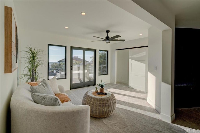 interior space featuring light carpet, a barn door, and ceiling fan