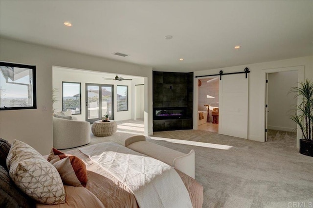 carpeted living room with a tiled fireplace and a barn door