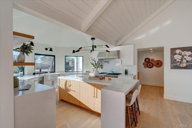 kitchen with white cabinetry, beam ceiling, a breakfast bar area, and a center island