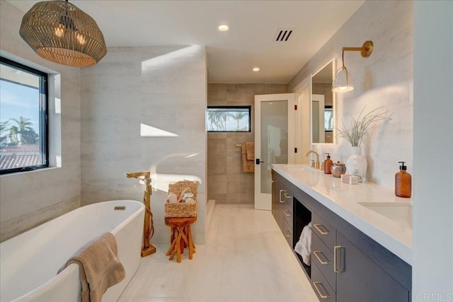 bathroom with vanity, a bathing tub, and tile walls