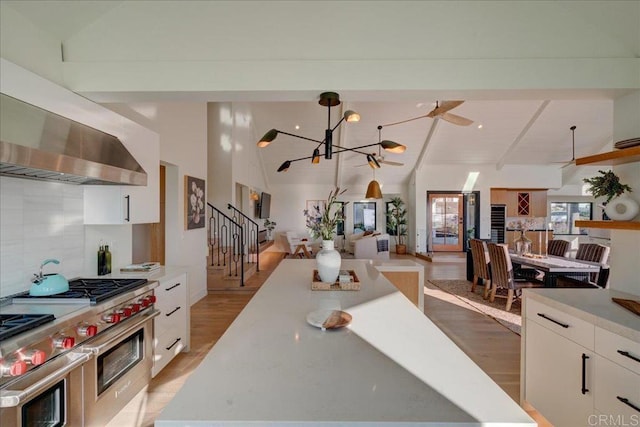 kitchen featuring range with two ovens, decorative backsplash, white cabinets, and lofted ceiling with beams