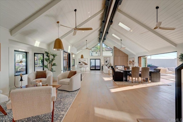 living room with a healthy amount of sunlight, ceiling fan, light hardwood / wood-style floors, and beamed ceiling