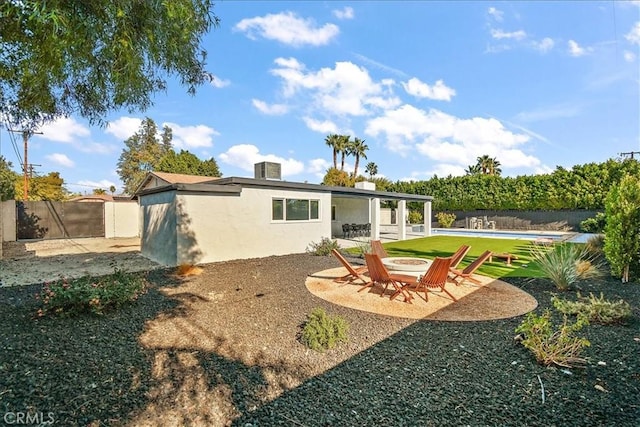 back of property with a fenced in pool, a patio, and a fire pit